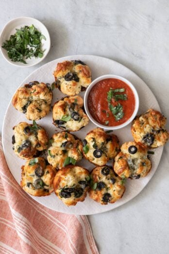 Round plate with recipe with a small dish of marinara and fresh chopped basil.