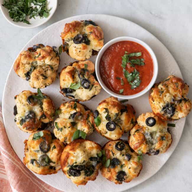 Round plate with recipe with a small dish of marinara and fresh chopped basil.