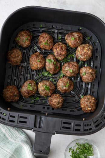 Air Fryer Meatballs after cooked in basket garnished with fresh parsley.