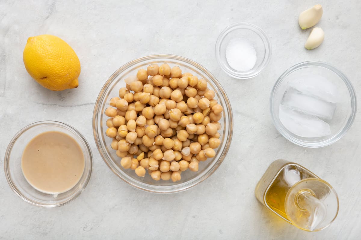 Ingredients for recipe: lemon, tahini, chickpeas, salt, ice cubes, garlic, and oil.