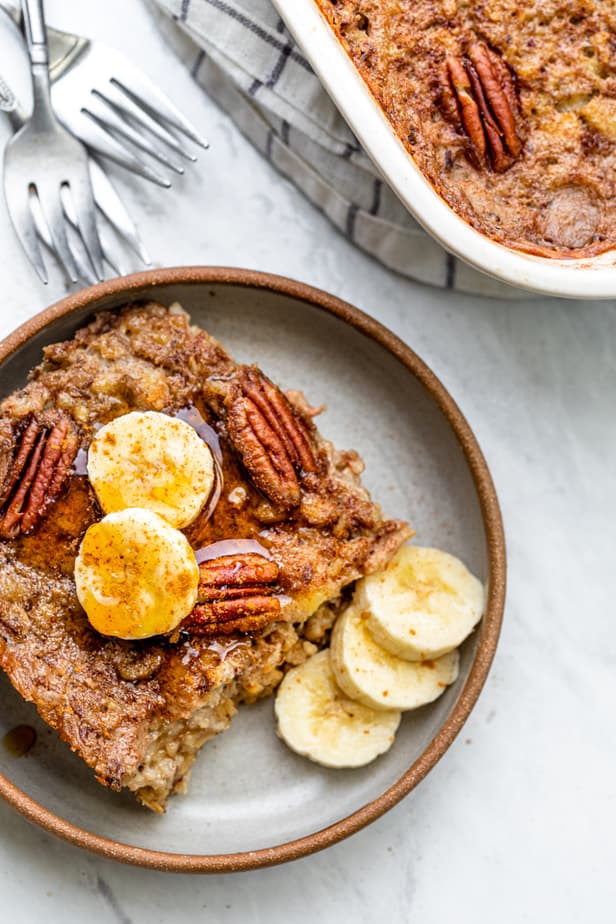 Slice of oatmeal served on plate topped with bananas and maple syrup