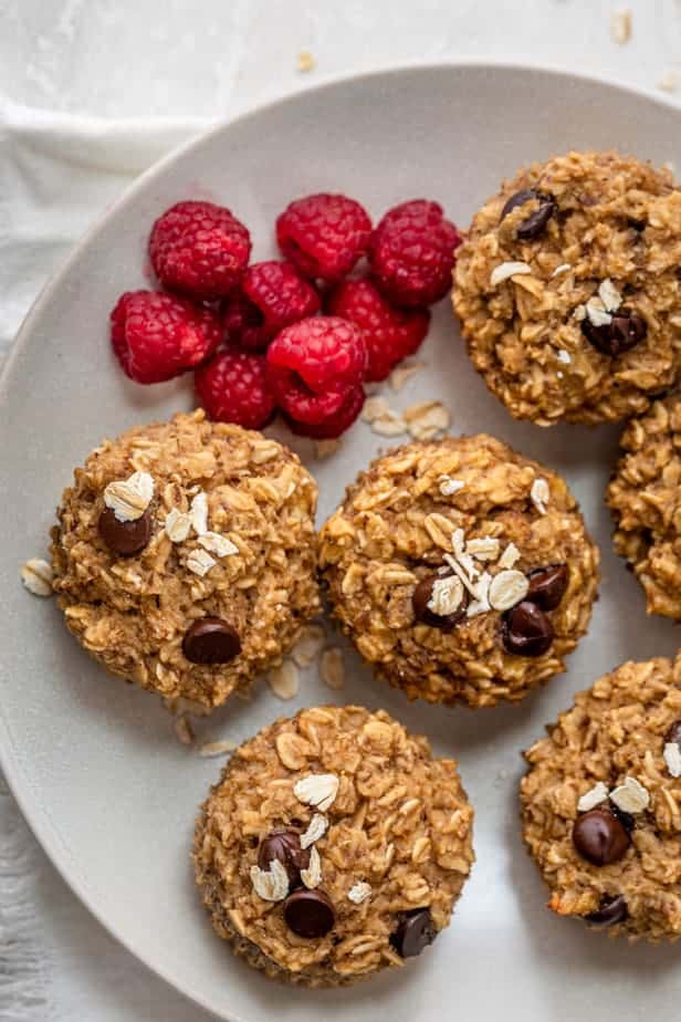 banana oatmeal cups on a plate with fresh raspberries