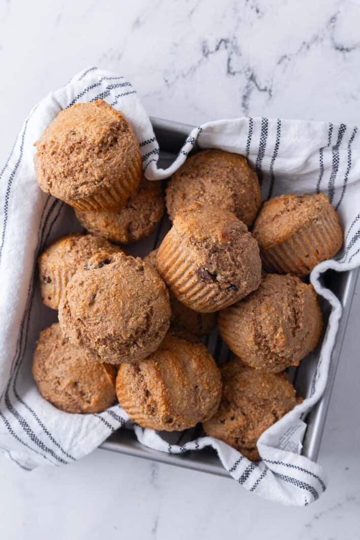 Whole wheat bran muffins in a clothed lined pan for serving.