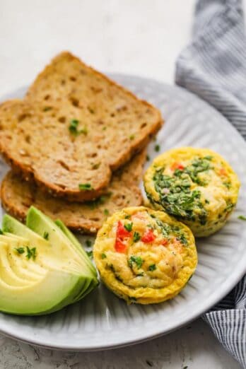 Breakfast egg cups served on a plate with toast and avocados