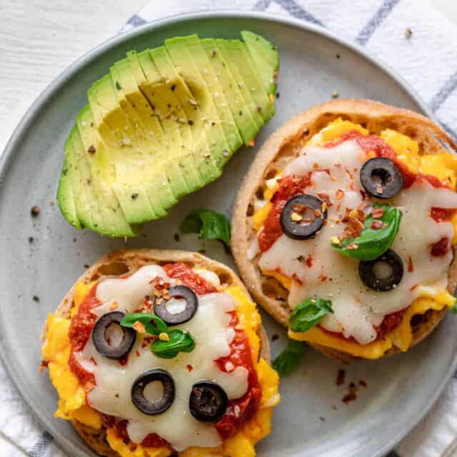 Breakfast English Muffin Pizzas on a plate with sliced avocados