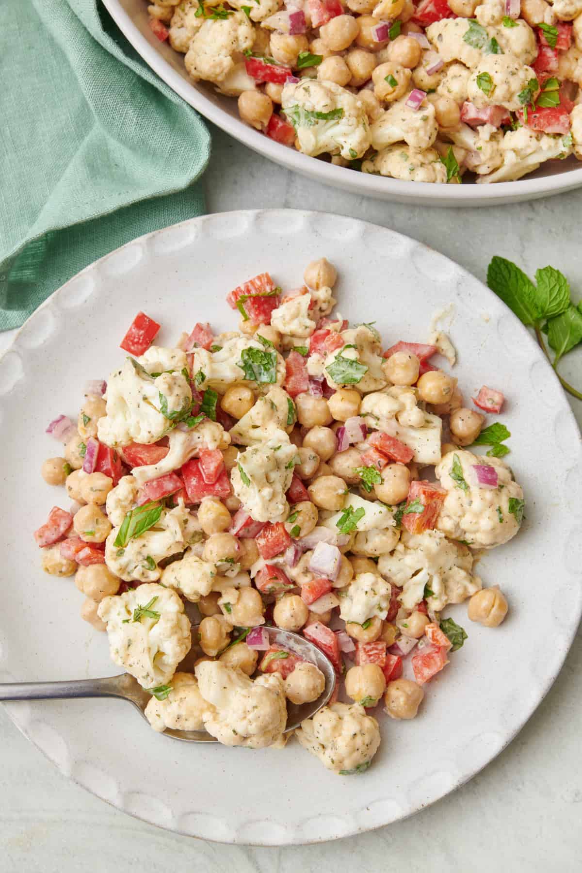 Plate of cauliflower salad with a large bowl next to it