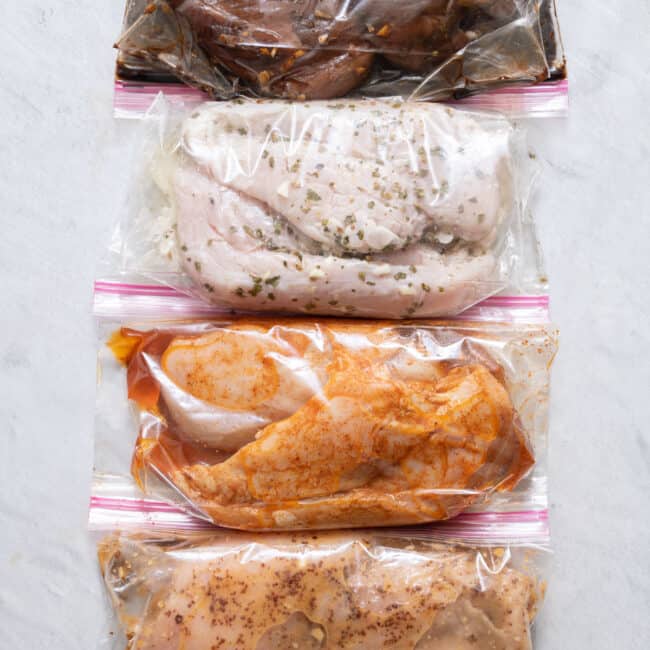 4 ziptop bags folded over with chicken breast each marinating in different recipes.