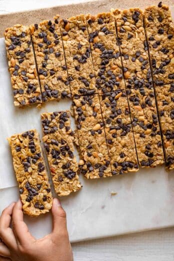 Chocolate Peanut Butter Granola Bars sliced with hand grabbing one