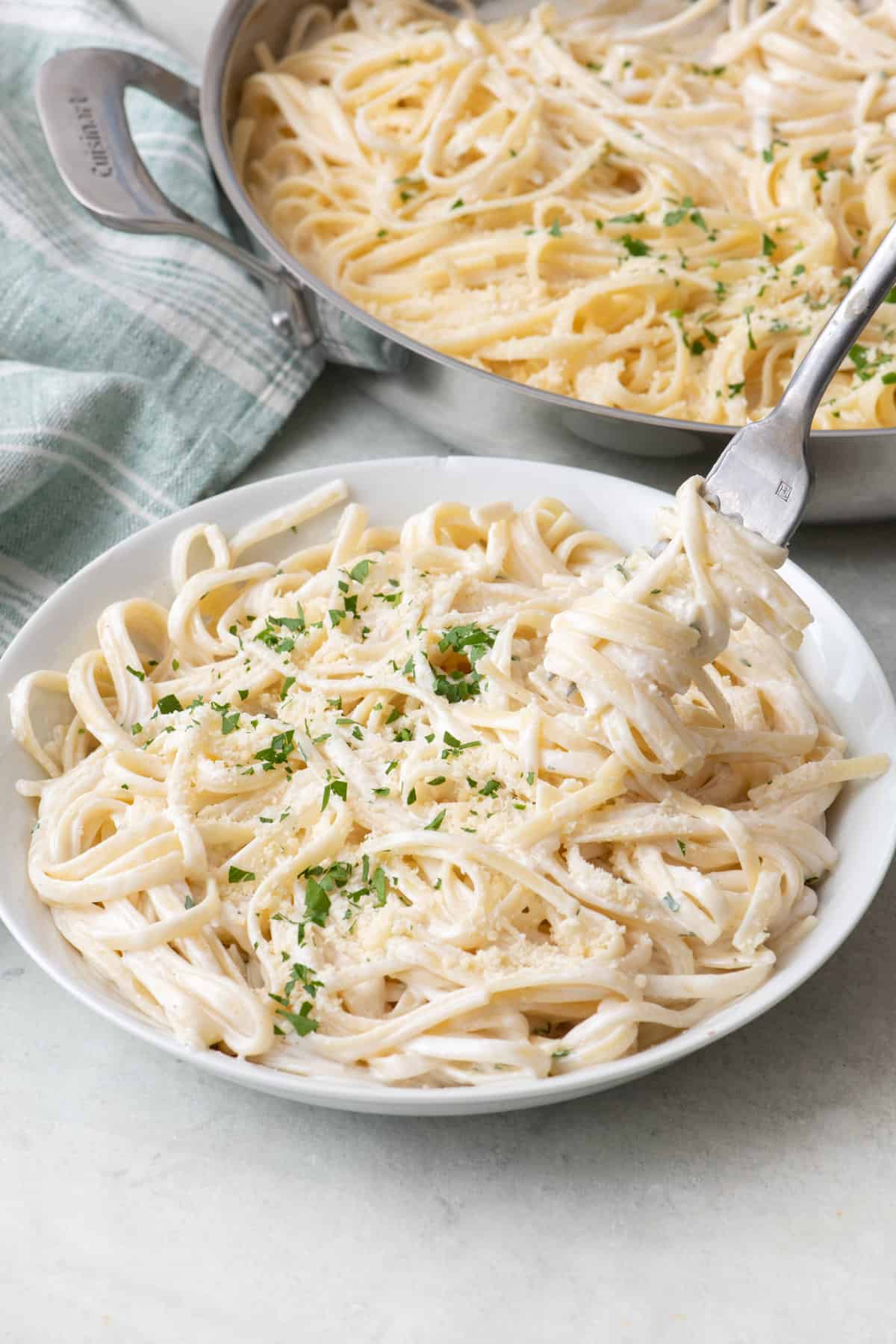 Fork lifting up a bite of cottage cheese alfredo pasta from bowl.