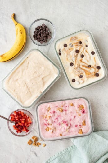 Cottage cheese icecrea in glass containers made with 3 different flavors: peanut butter chocolate chip, banana cream, and strawberry cheesecake. Extra toppings nearby.