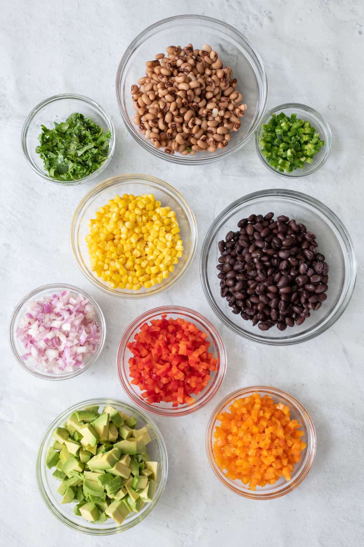 Prepared vegetables and ingredients for salad recipe in individual bowls.