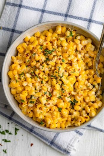 Large bowl of creamed corn with spoon inside for serving