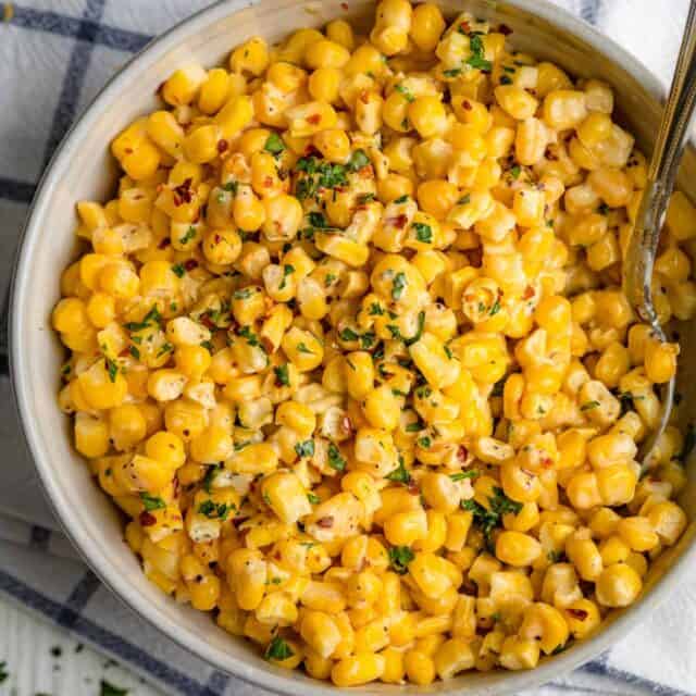 Large bowl of creamed corn with spoon inside for serving