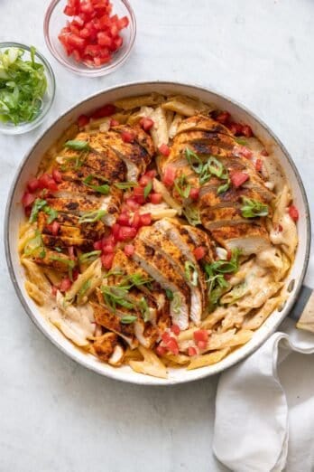 Skillet of the creamy cajun pasta garnished with roma tomatoes and green onions.