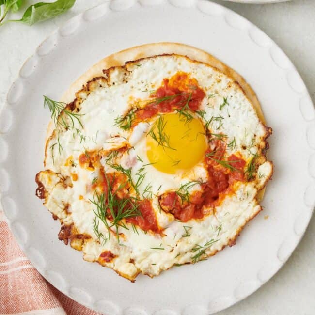 Crispy fried feta eggs with harissa on a tortilla shell garnished with fresh dill.