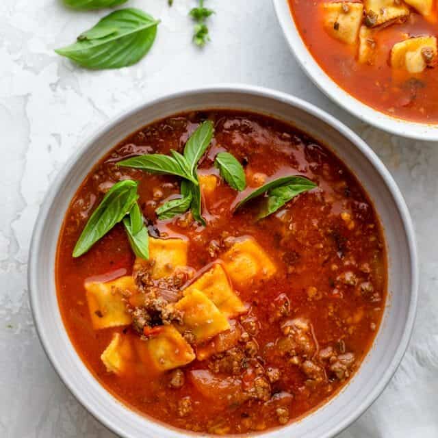 Large bowl of ravioli soup made with ground beef and garnished with basil