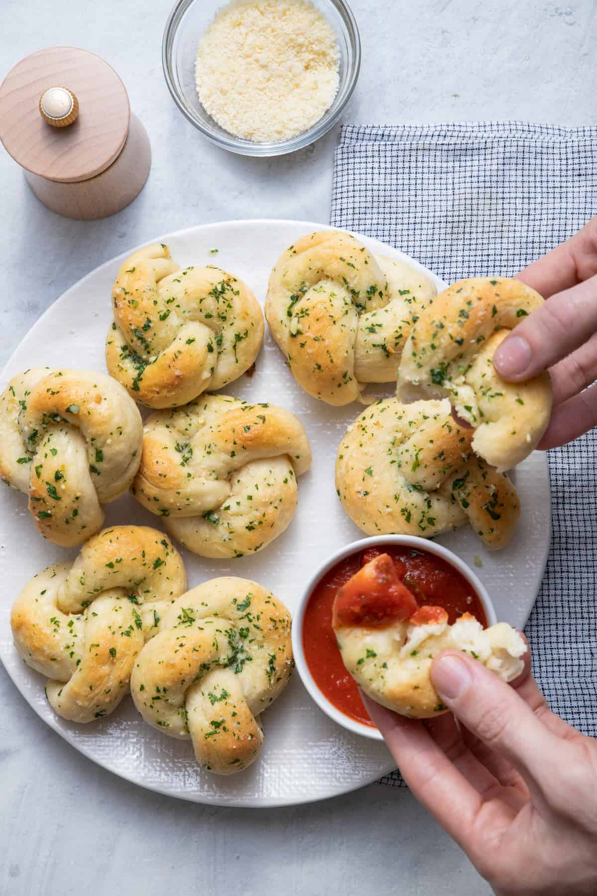 Garlic knots dipping into marinara sauce