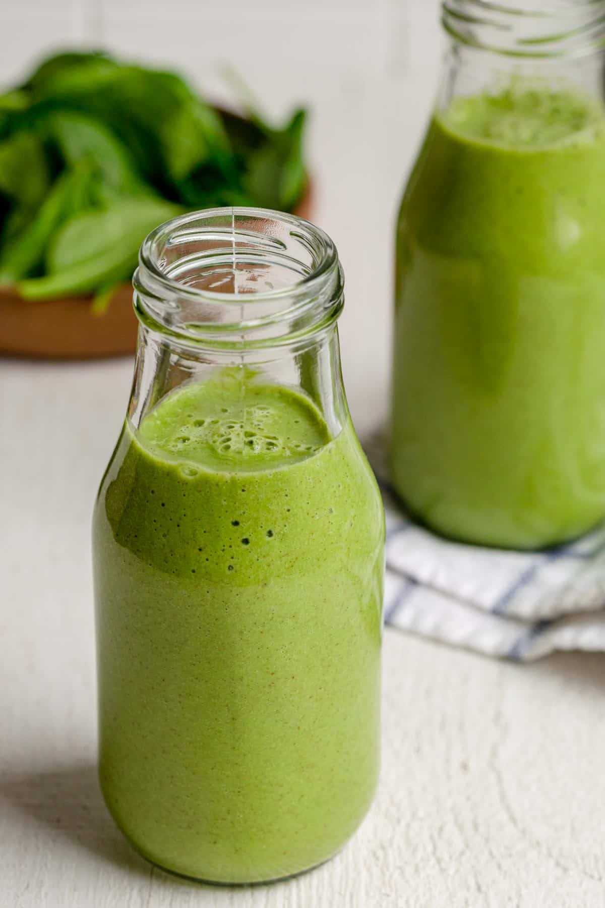 Angle shot of two glasses of glowing green smoothie with raspberries on top