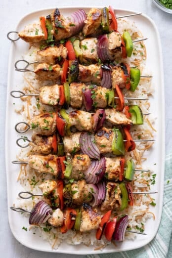 Grilled Chicken Kabobs on a white long platter served over Lebanese rice