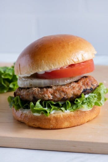 Assembled grilled turkey burger with lettuce, tomato, onion, and mayo.