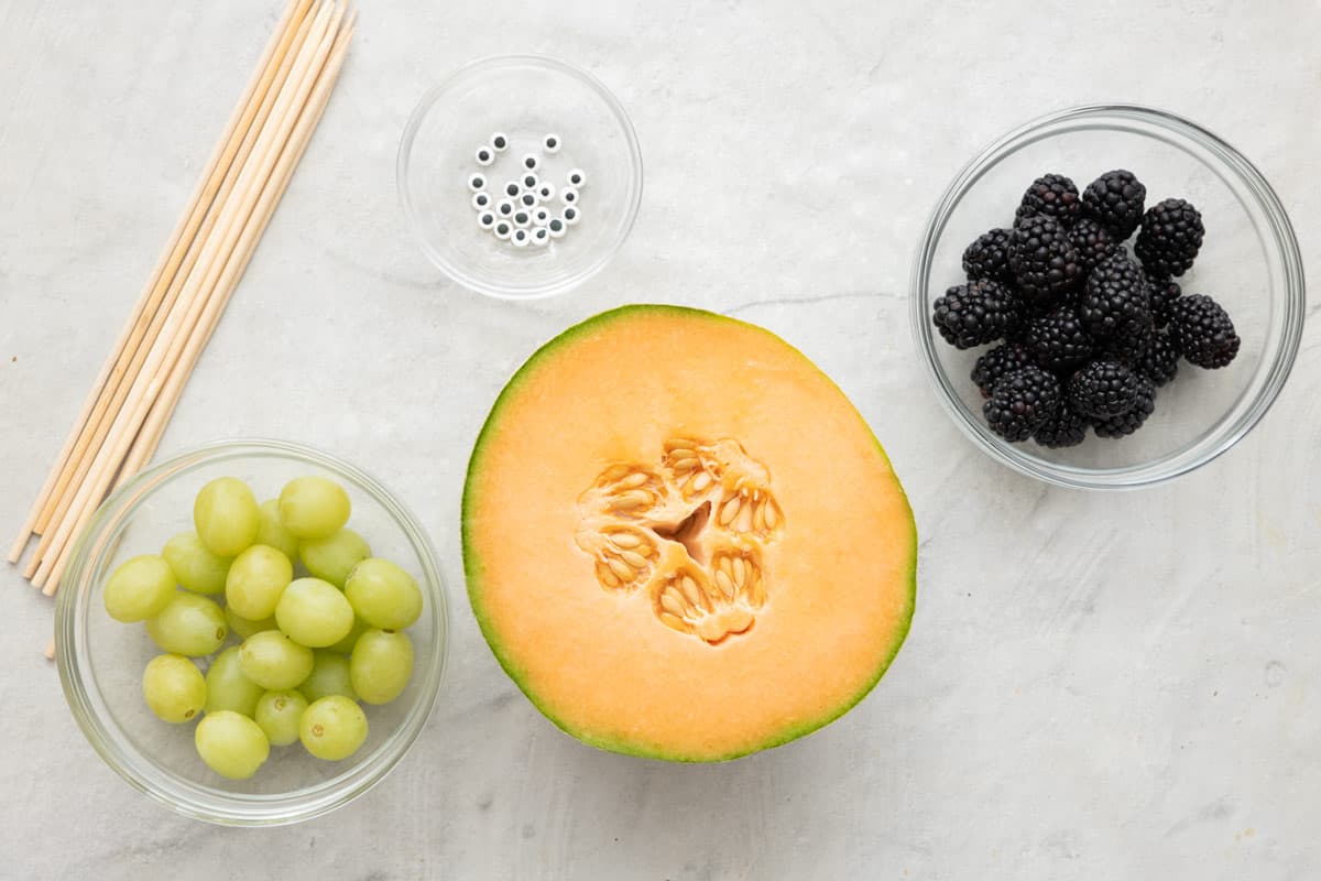 Ingredients for recipe: green grapes, cantaloup, blackberries, and candy eyes.