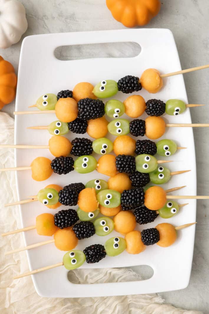 Halloween fruit kabobs on a platter, made with grapes, blackberries, and cantaloup.