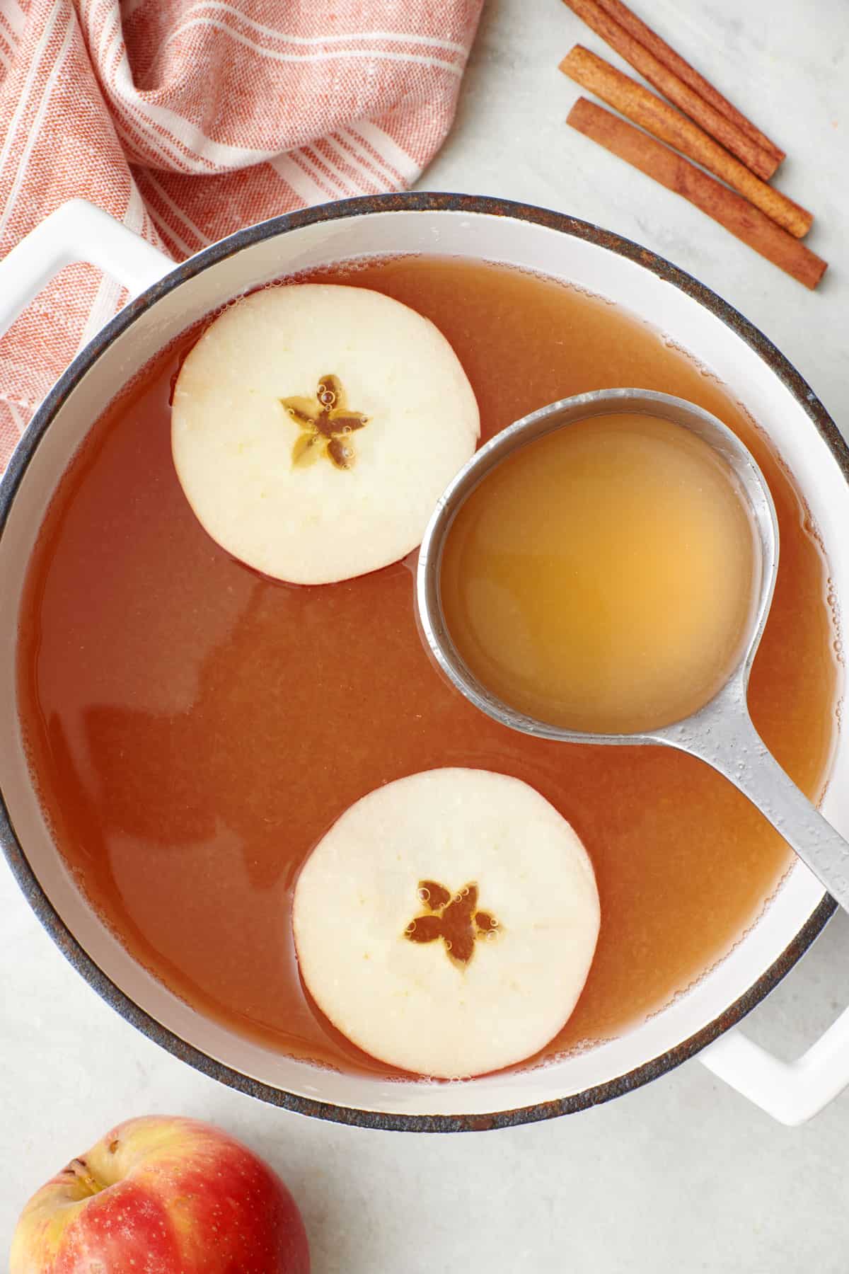 Pot of homemade apple cider with a ladle scooping some up.