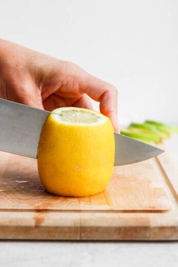 Large lemon on cutting board getting cut with large knife