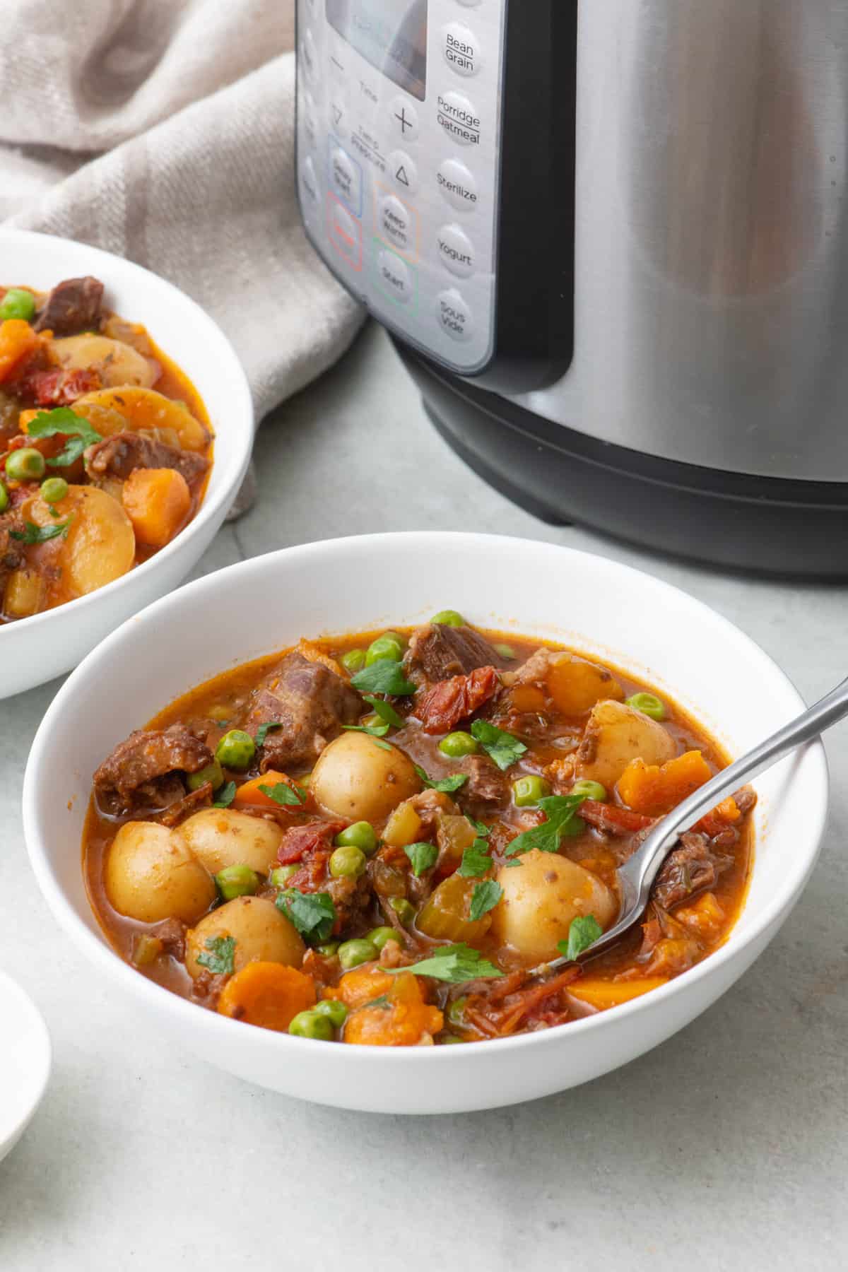 Two bowls of beef stew next to instant pot.