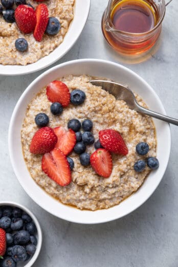 Two bowls of steel cut oatmeal made in the instant pot topped with berries and honey