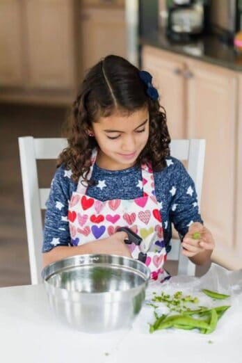 My daughter using scissors to trim off ends of green beans