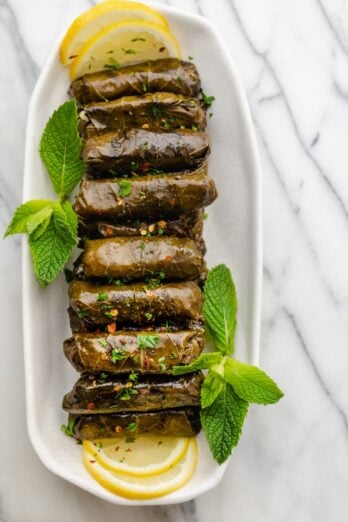 Final stuffed grape leaves lined up on a long plate