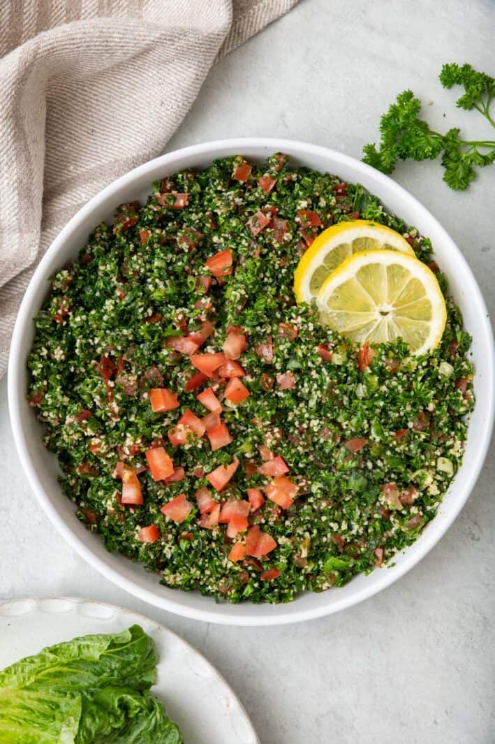 Final plated bowl of tabbouleh salad garnished with lemon slices.