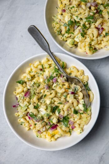 Two bowls of macaroni egg salad with spoon in one bowl