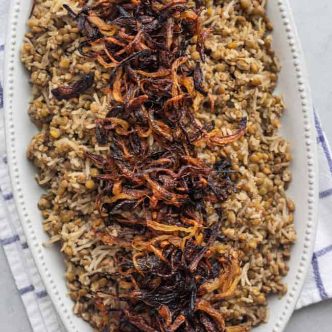 Mujadara topped with crispy onions on a large platter.