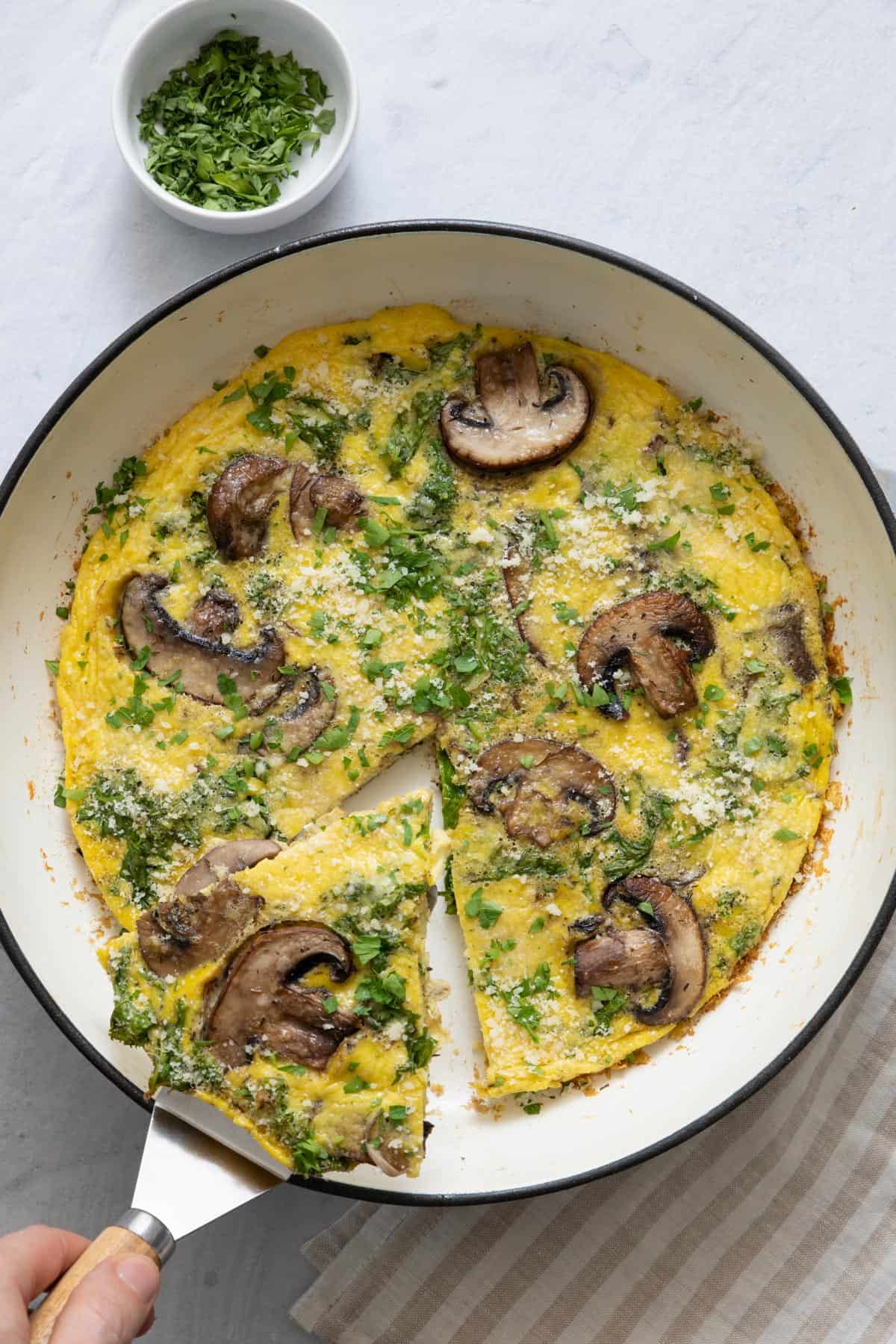 A slice of frittata being removed from baking dish with pie spatula.