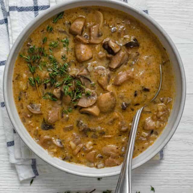 Large bowl of mushroom soup with wild rice and spoon inside bowl