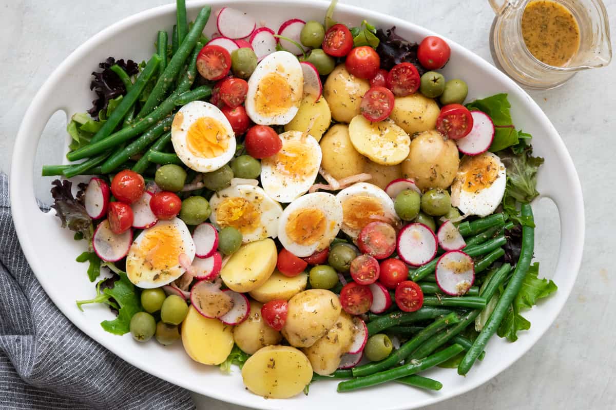 Fork lifting up a serving from a platter of Nicoise salad.