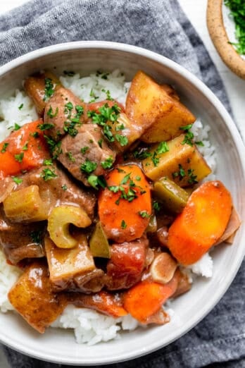 Bowl of oven roasted beef and vegetables over white rice in a white bowl.