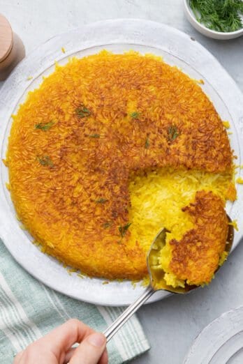 Spoon scooping some of the crispy Persian rice to show the inside fluffy yellow rice