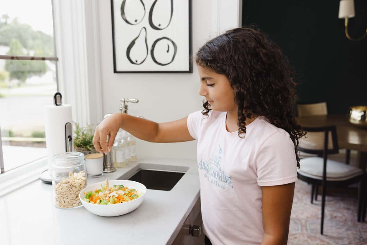 Carine sprinkling nuts on salad