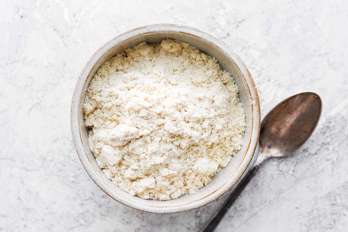 Whey protein powder in a bowl with a spoon next to it