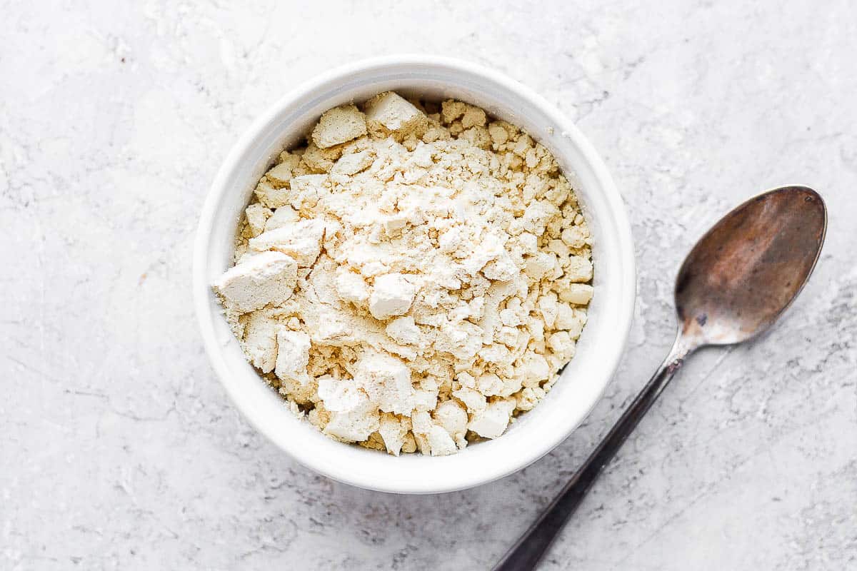 Green protein powder in a bowl with a spoon next to it