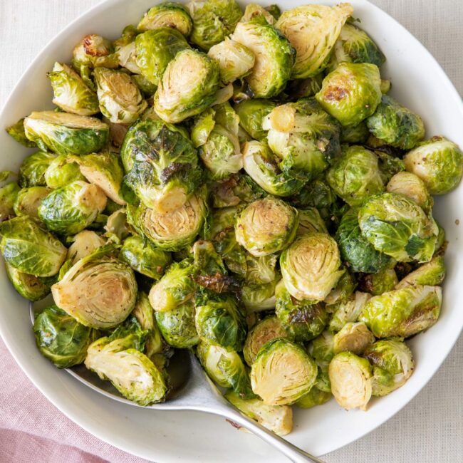 Large bowl of roasted brussel sprouts with a spoon added in.