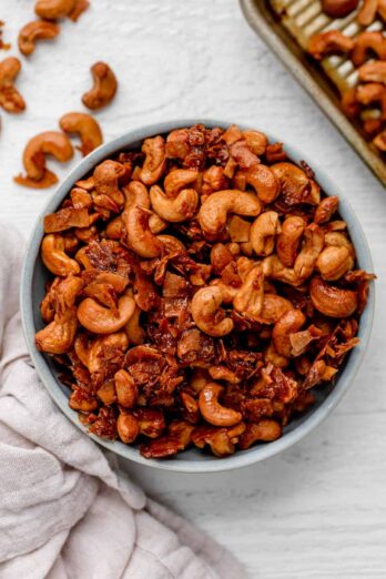 Large bowl of roasted cashews with coconut on white background