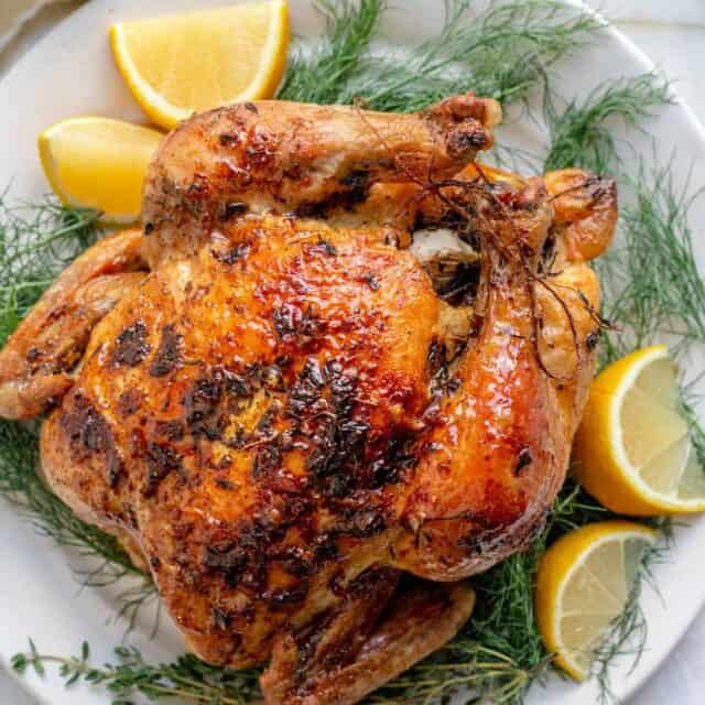 White plate with roasted chicken with lemon and herbs