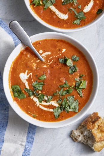 bowl of Roasted red pepper soup bowl with baguette next to it