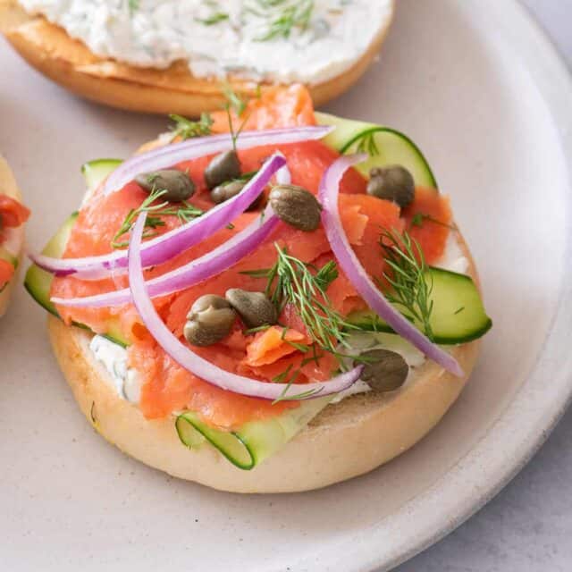 Smoked salmon bagel sandwich topped with cucumbers, capers and onions