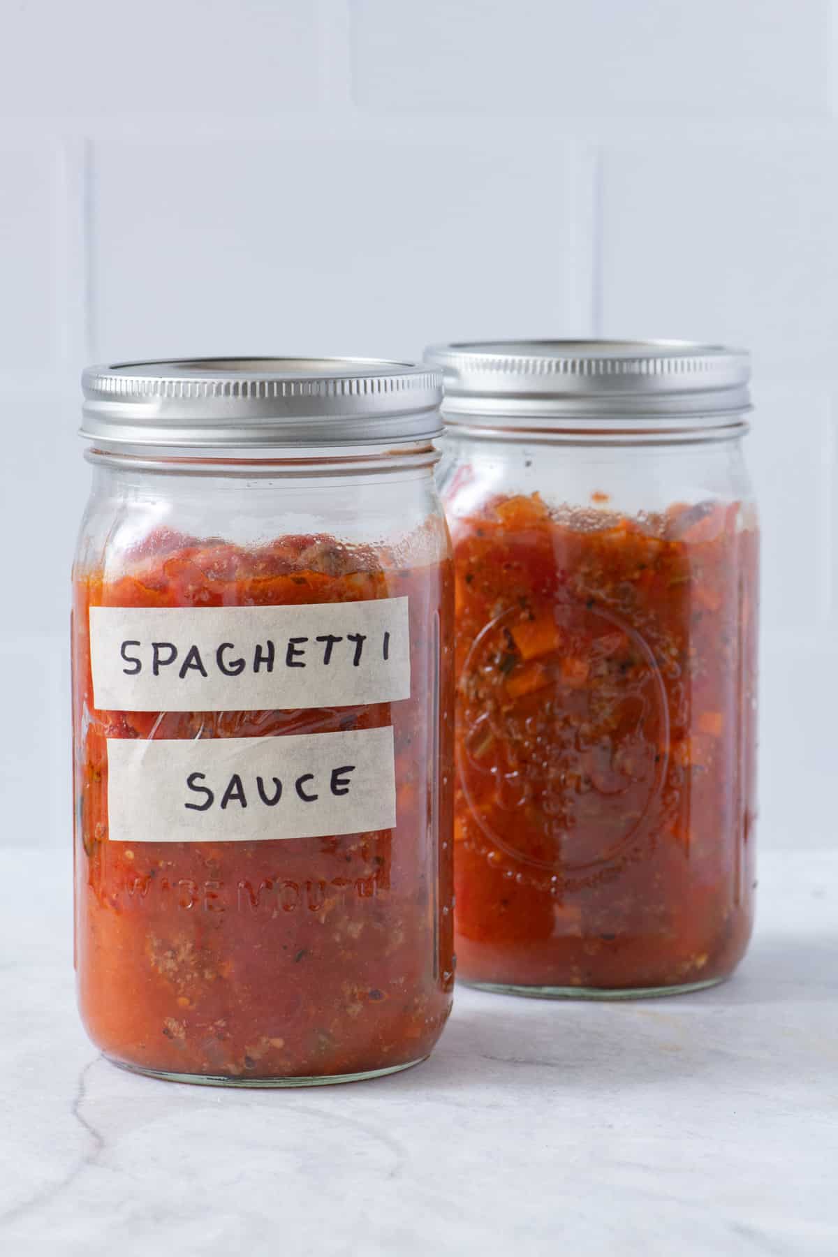 Spaghetti sauce in two large mason jars one with a label.