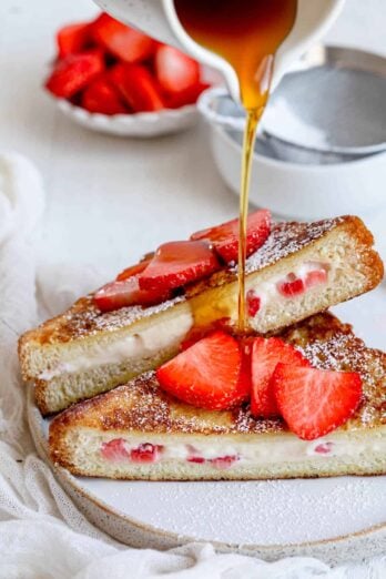 Angle shot of stuffed french toast showing the cream cheese filling with maple syrup pouring on top